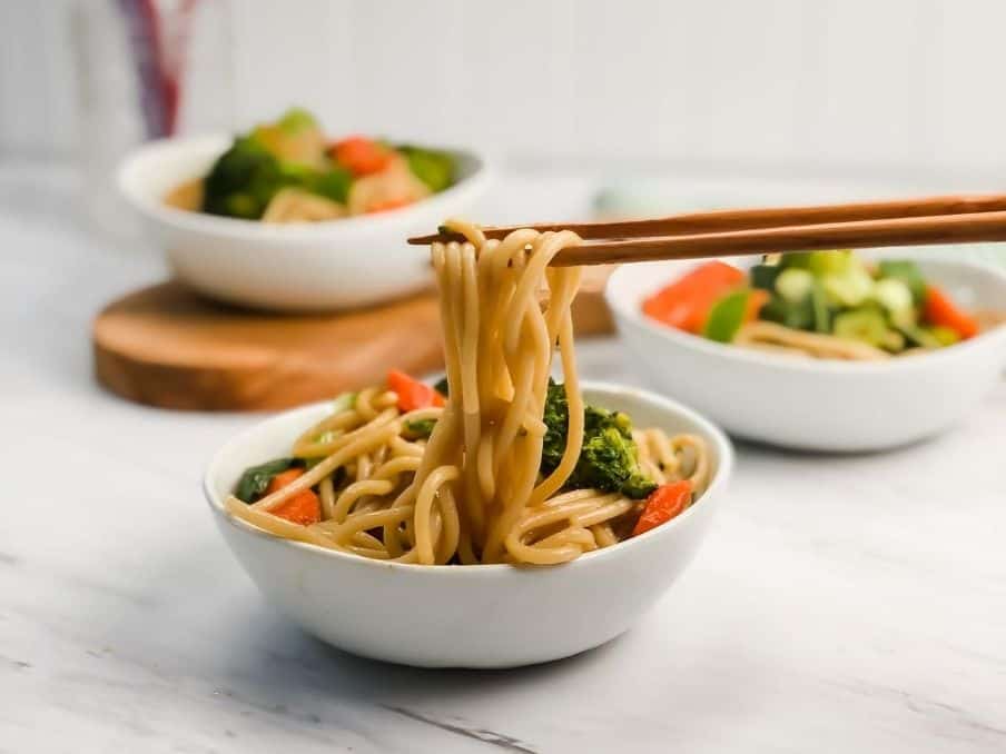 gluten free and vegan lo mein in a white bowl with chopsticks on a marble table // livingbeyondallergies.com
