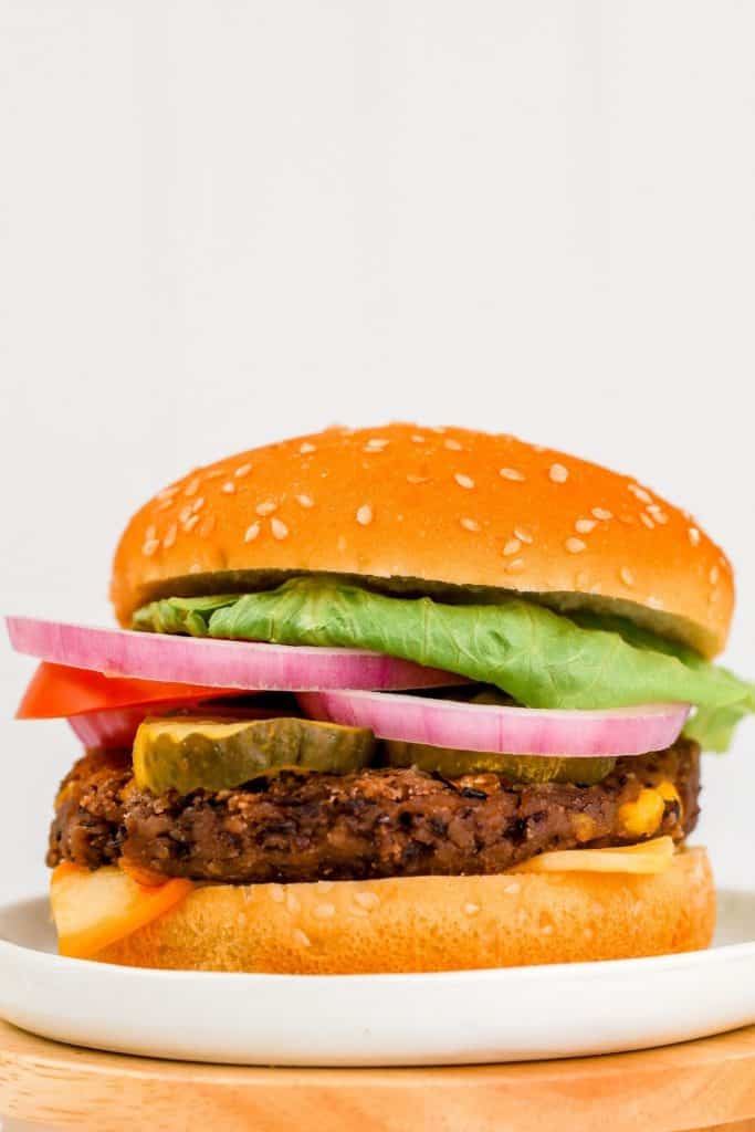 an unclose image of a vegan black bean burger on a white plate in front of a white background