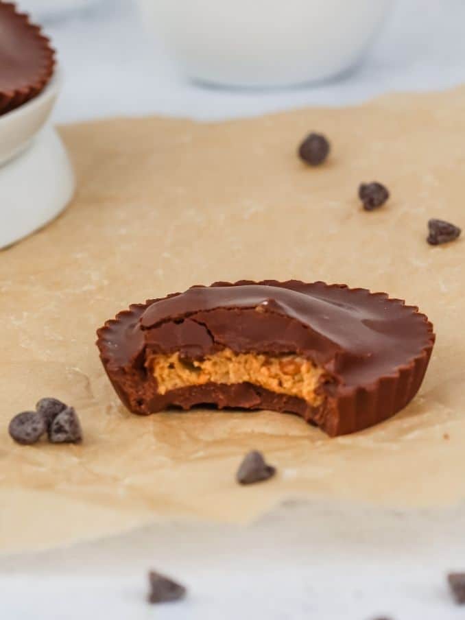 a close up of a sun butter cup is shown on brown parchment paper with a bite taken out of it