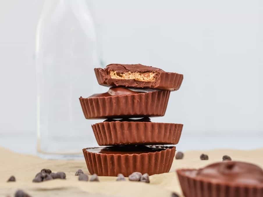 a stack of sunbutter cups are shown on brown parchment paper with mini chocolate chips scattered around the scene