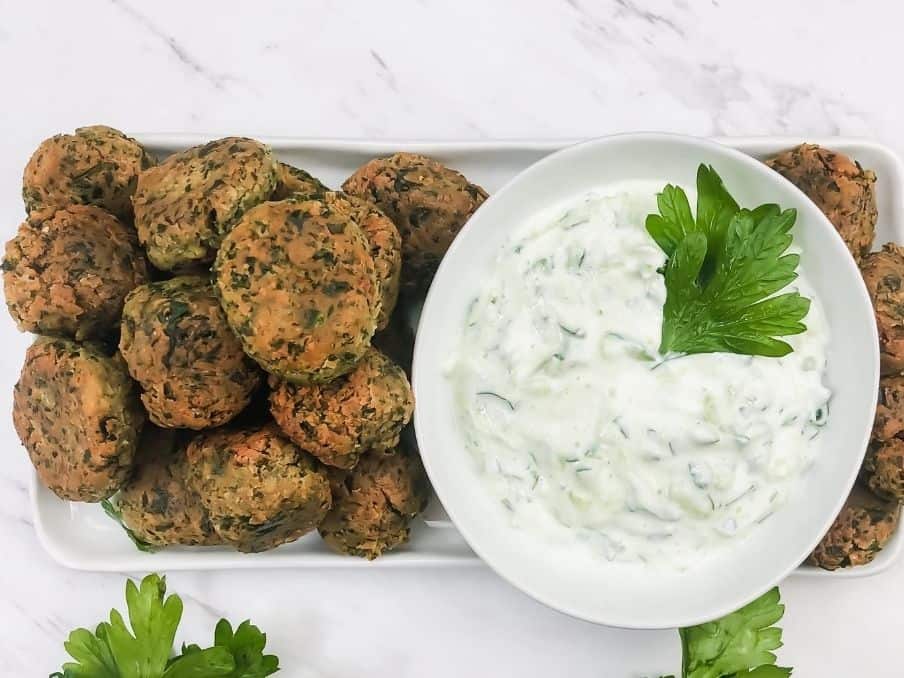 classic falafel that is gluten free and vegan on a plate with a bowl of yogurt dipping sauce on a white marble tale // livingbeyondallergies.com