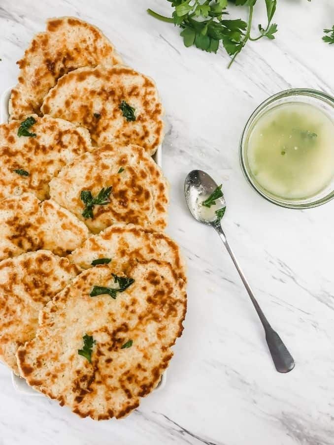 gluten free flatbread in a pile on the white marble table with a spoon and garlic butter in a bowl // livingbeyondallergies.com