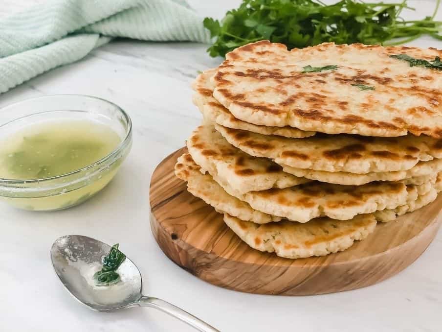 closeup of gluten free flatbread in a stackc on a white marble table with a spoon and garlic butter in a bowl // livingbeyondallergies.com