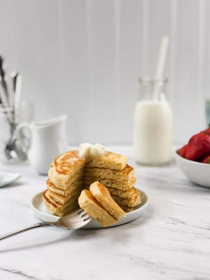 fork with gluten free vegan pancakes ready to eat on a white plate // livingbeyondallergies.com