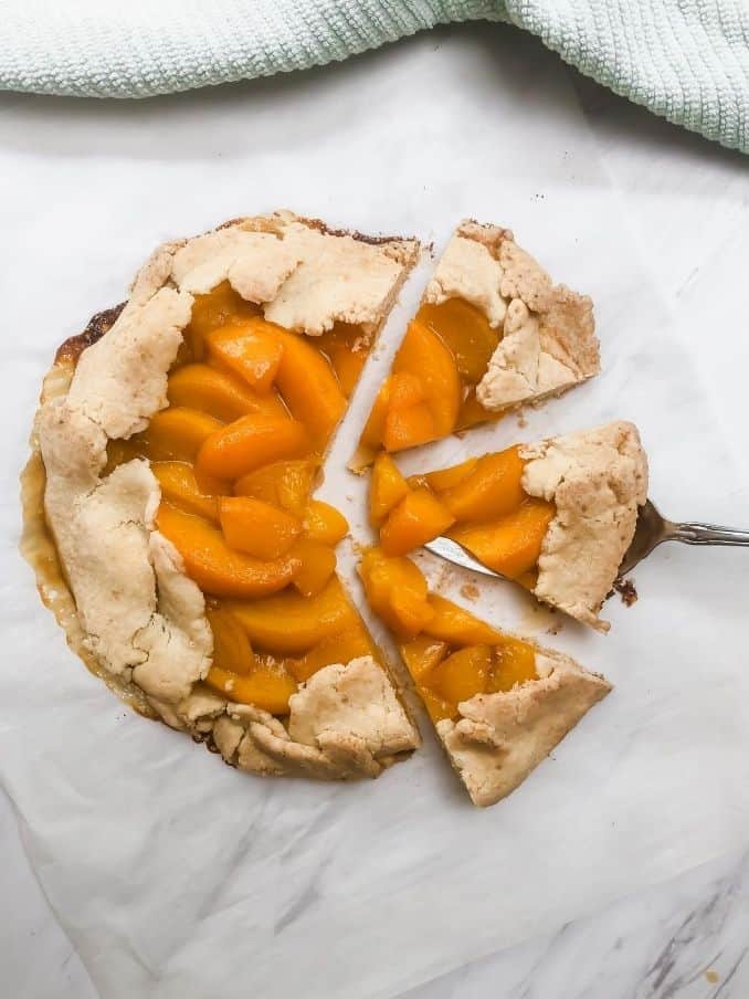 peach galette with three slices ready to serve on a white marble top // livingbeyondallergies.com