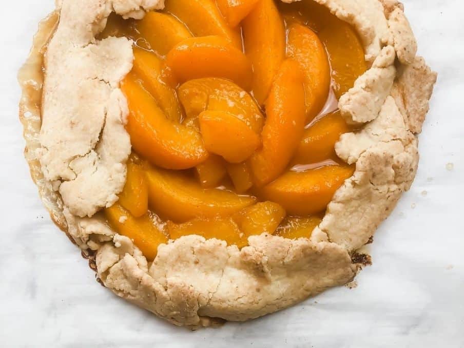 peach galette close up on a white marble countertop // livingbeyondallergies.com