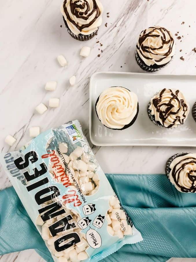 decorating gluten free vegan hot chocolate cupcakes with marshmallows and a blue towel