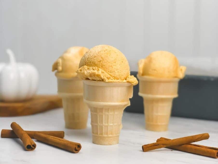 pumpkin chai ice cream in three cones with cinnamon sticks on a white marble table // livingbeyondallergies.com