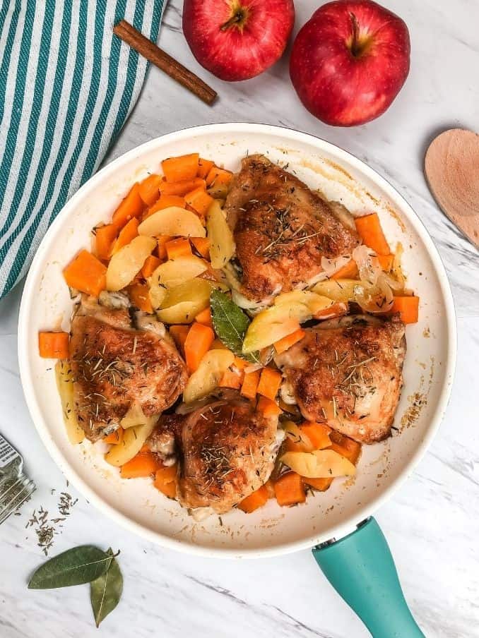 apple cider chicken in the skillet surrounded by ingredients on the countertop
