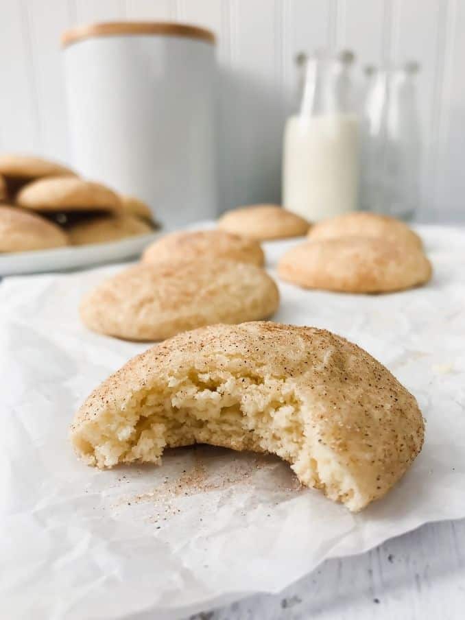 close up of a gluten free snickerdoodle cookie with a bite taken out of it resting on parchment paper on the countertop // livingbeyondallergies.com