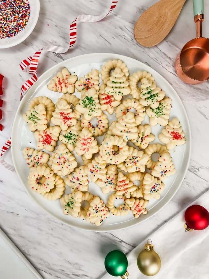 plate filled with gluten free spritz covered in sprinkles on the countertop surrounded by seasonal decor // livingbeyondallergies.com