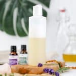 a white bottle filled with hypoallergenic shampoo is resting on a wood board on the kitchen countertop. ingredients like essential oils, fresh lavender, and oils are in the background
