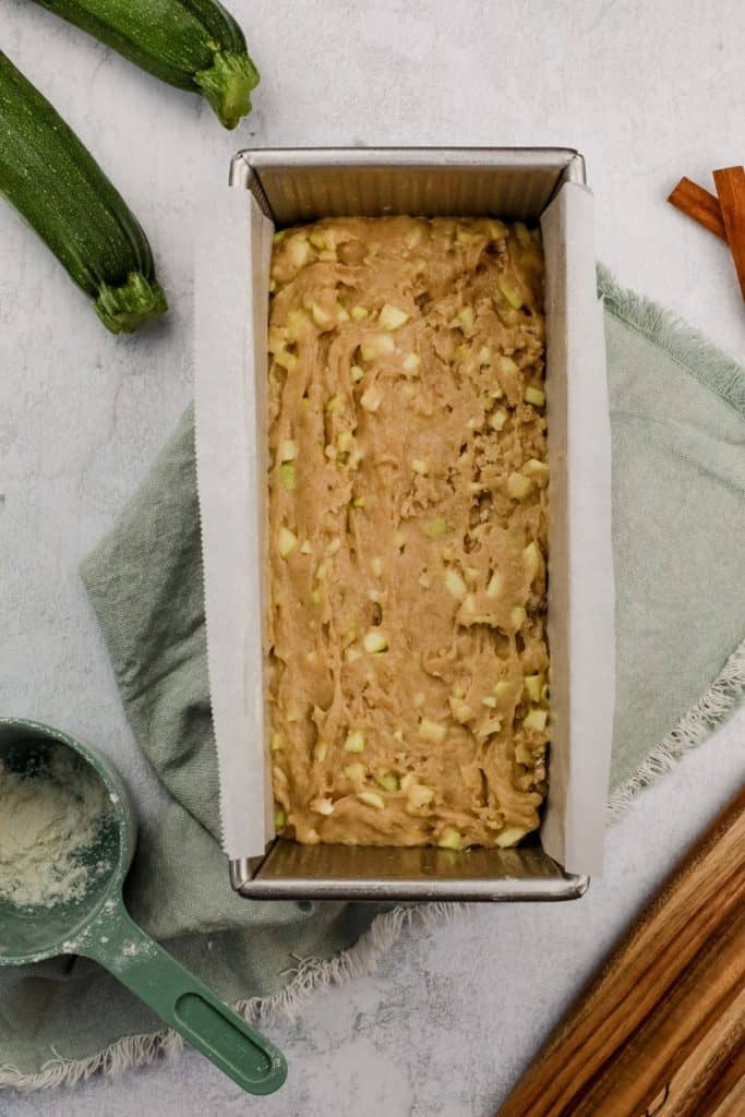 zucchini bread batter in prepared loaf pan on the kitchen countertop 