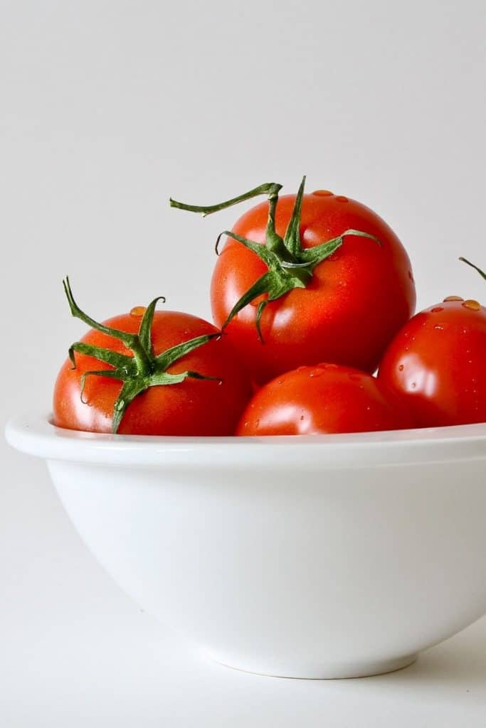 a big bowl of red tomatoes is on a white background