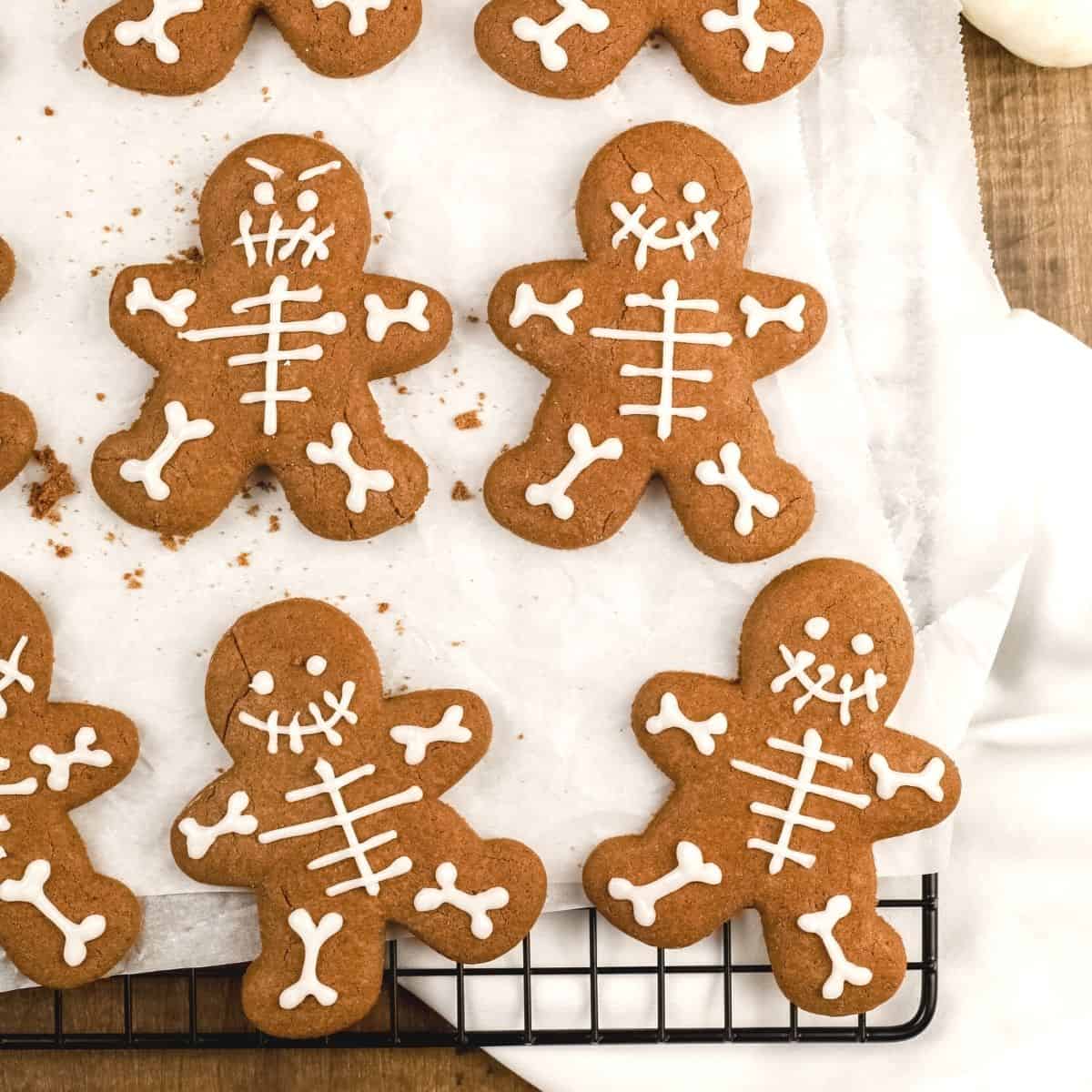 chocolate skeleton cookies are on a white parchment paper on a cooling rack
