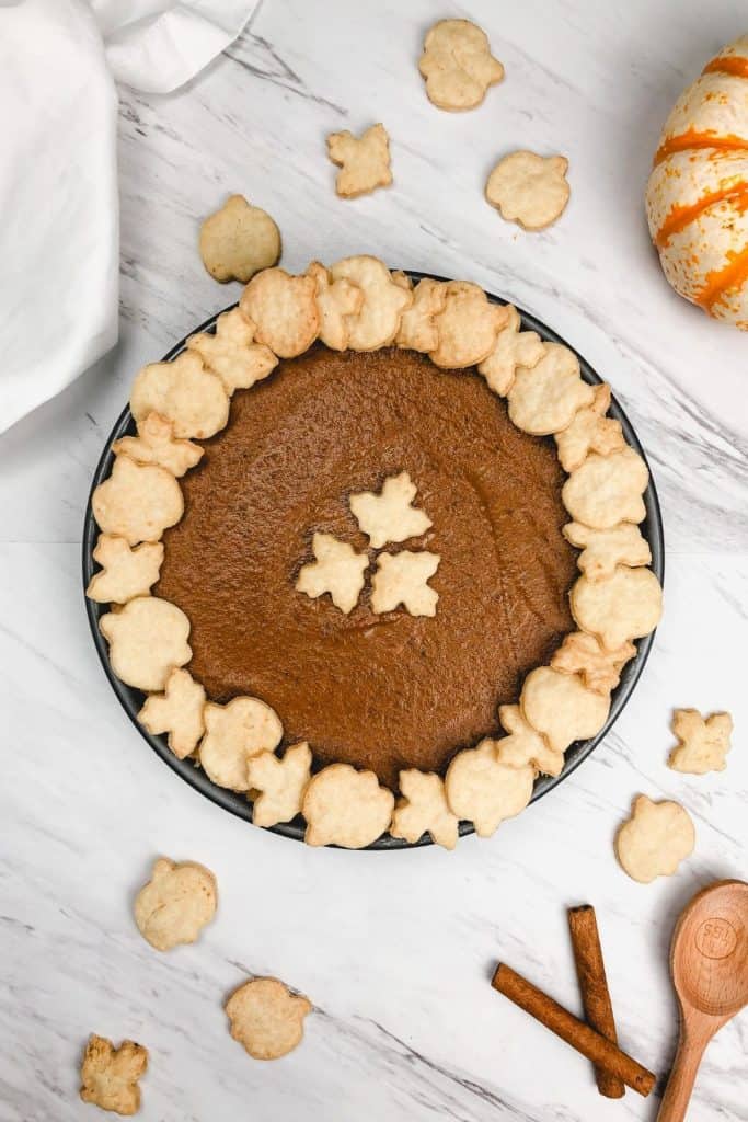 a whole pumpkin pie is shown with pumpkins and spices surrounding it