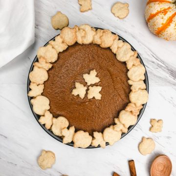a whole pumpkin pie is shown with mini pumpkins and spices surrounding it