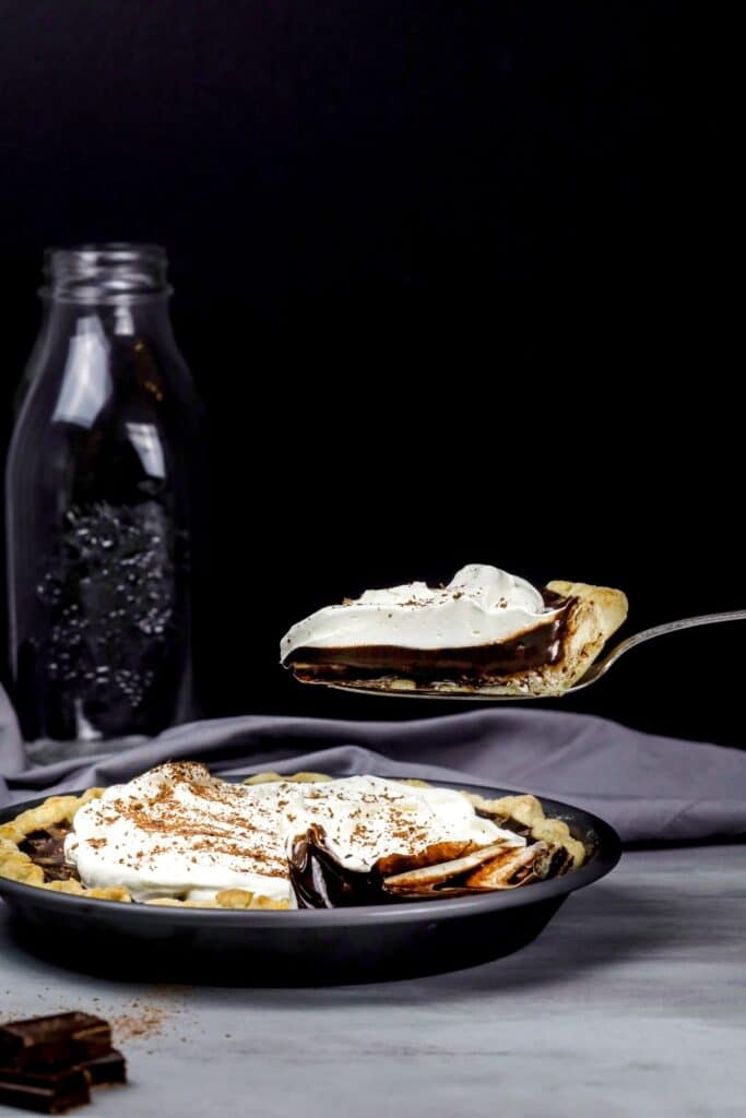 lift a slice of chocolate pie in front of a dark background