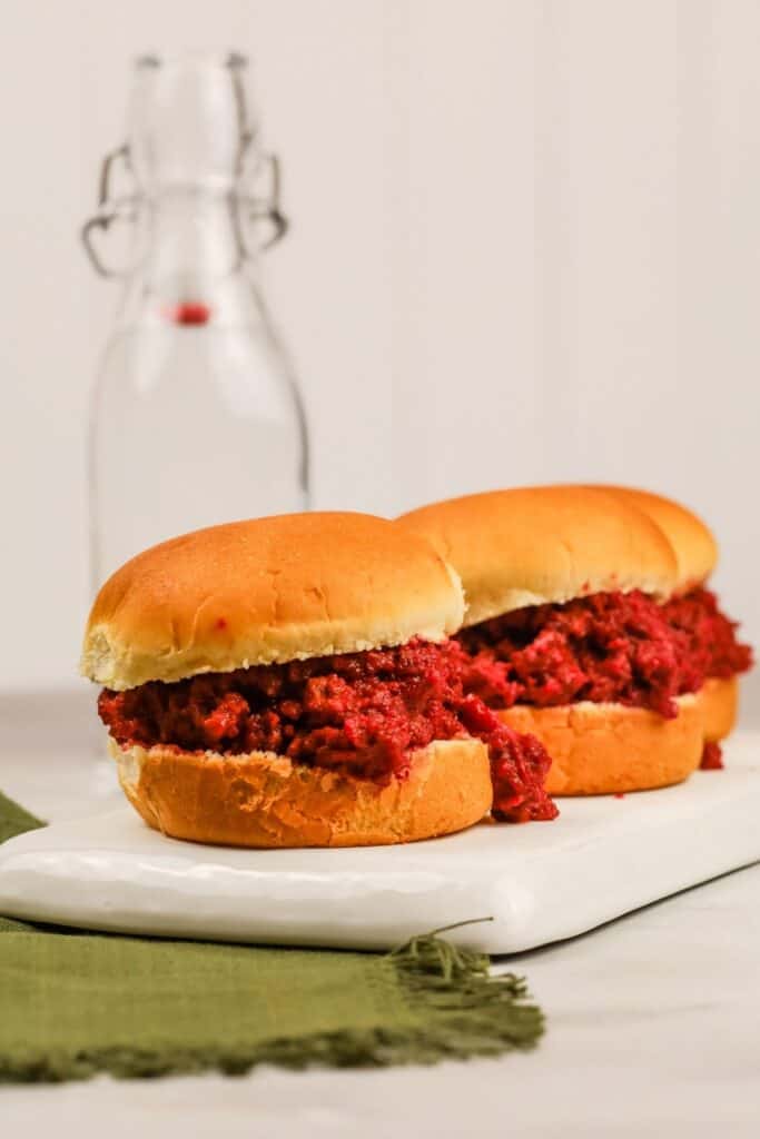 row of three tomato free sloppy joes on a plate with a green napkin 