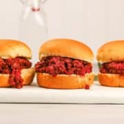 three tomato free sloppy joes on a plate in front of a white background