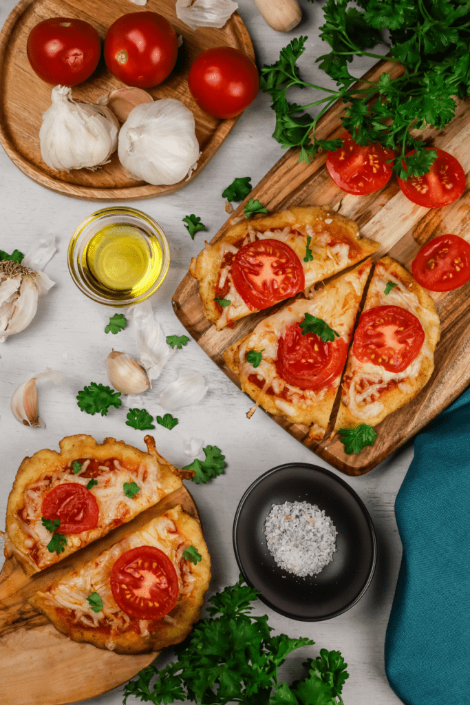 gluten free naan pizza on wood platters with ingredients surrounding it