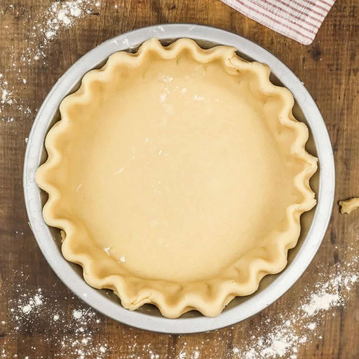 overview of a vegan pie crust in a pan before baking on a wood table