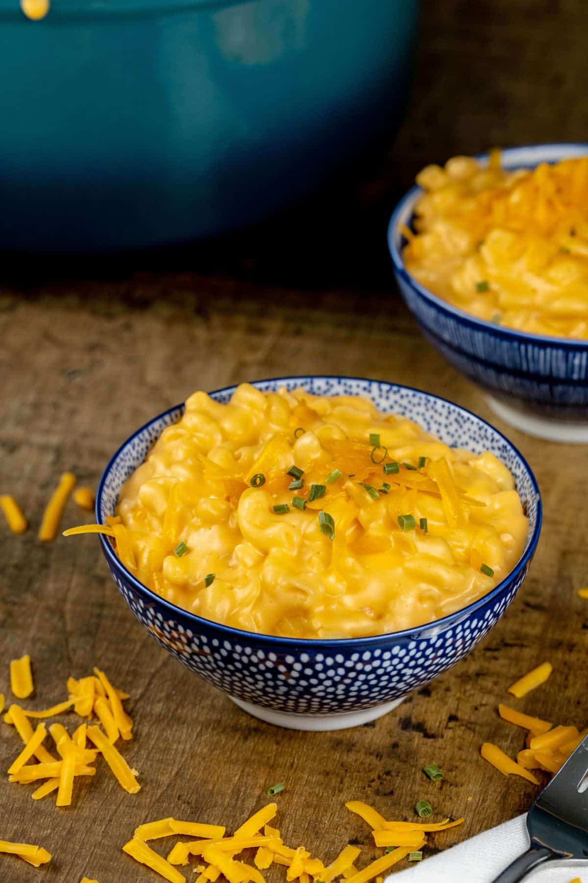 two bowls filled with Mac and cheese and extra cheese sprinkled around the bowls