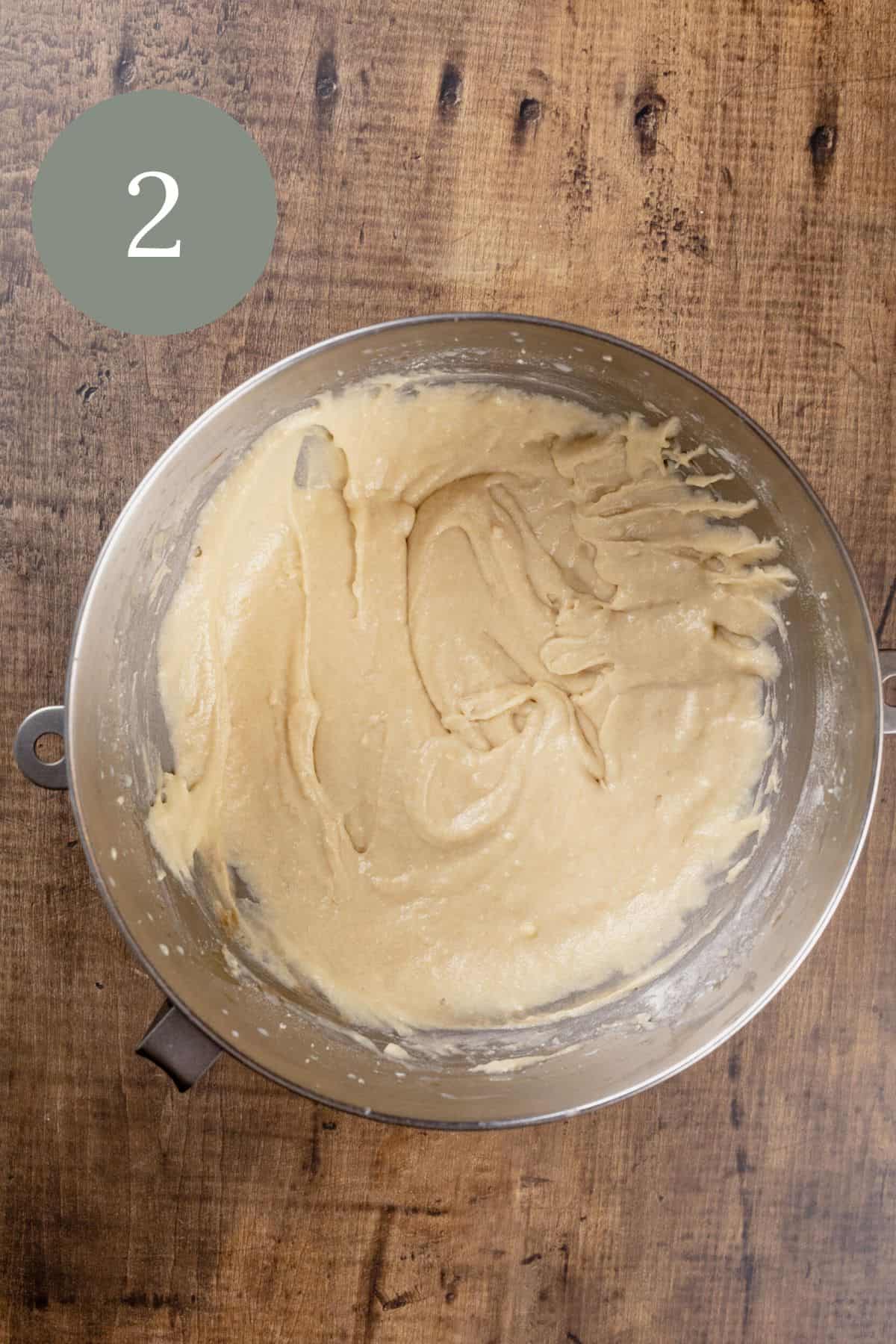 fully mixed cupcake batter in the silver mixing bowl on the wood tabletop