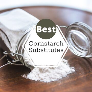 a glass jar filled with starch is tipped over onto a dark wood board. text appears on the image that reads best cornstarch substitutes