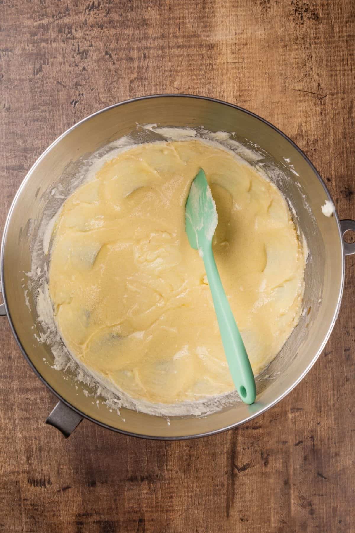 mixing the wet ingredients in a silver bowl with a green spatula in the batter