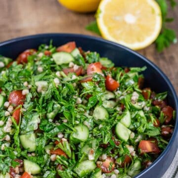 close up gluten free tabbouleh in blue bowl with sliced lemons