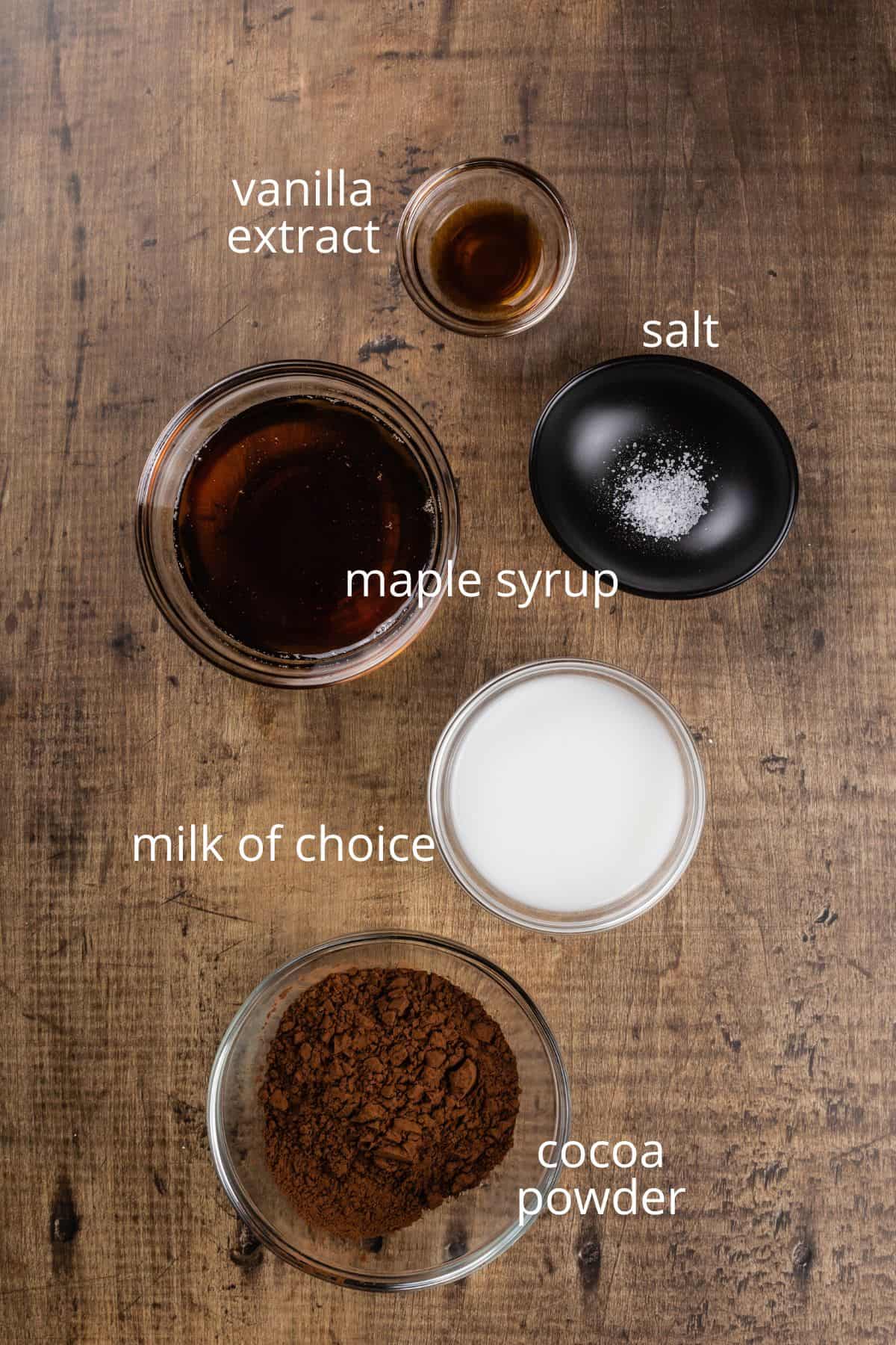 ingredients for vegan chocolate sauce in various bowls on the wood table