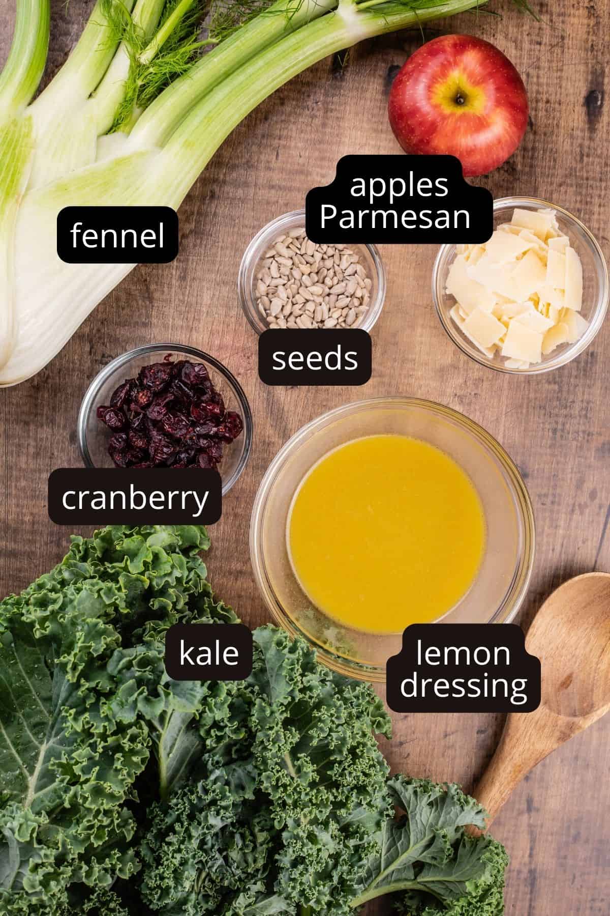 ingredients for a kale and cranberry salad in various glass bowls on a wood tabletop.