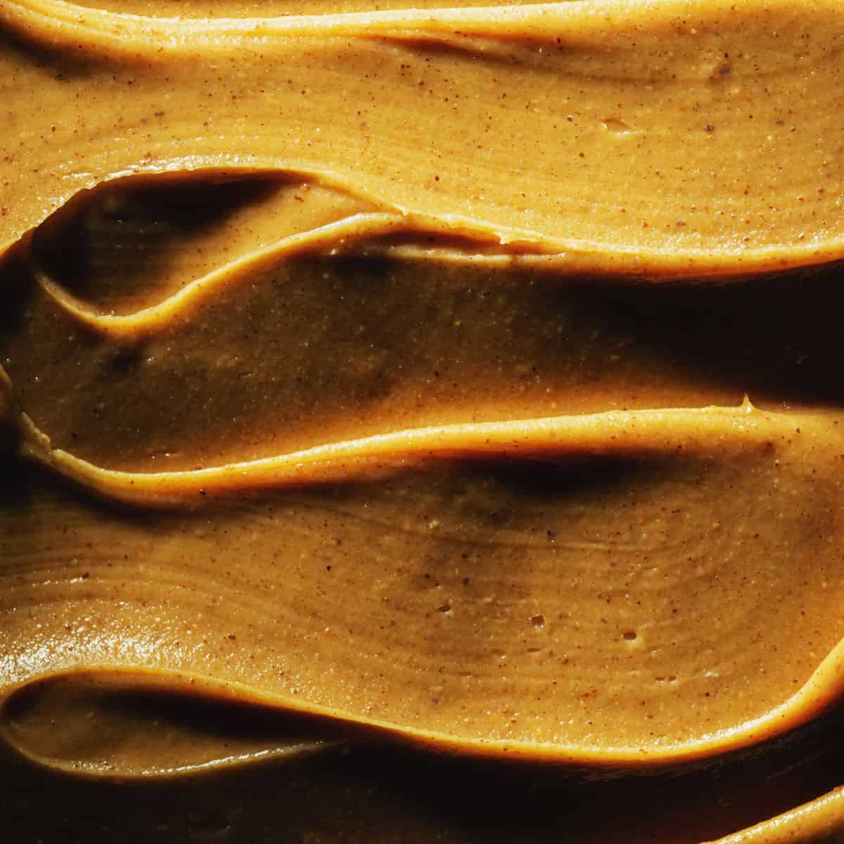 up close of smooth creamy peanut butter swirled around on a plate.