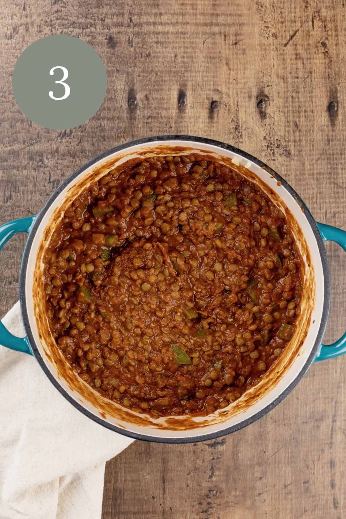 the finished lentils in a blue cooking pot. a white towel is under the pot. a green circle with the number 3 is in the top left corner.