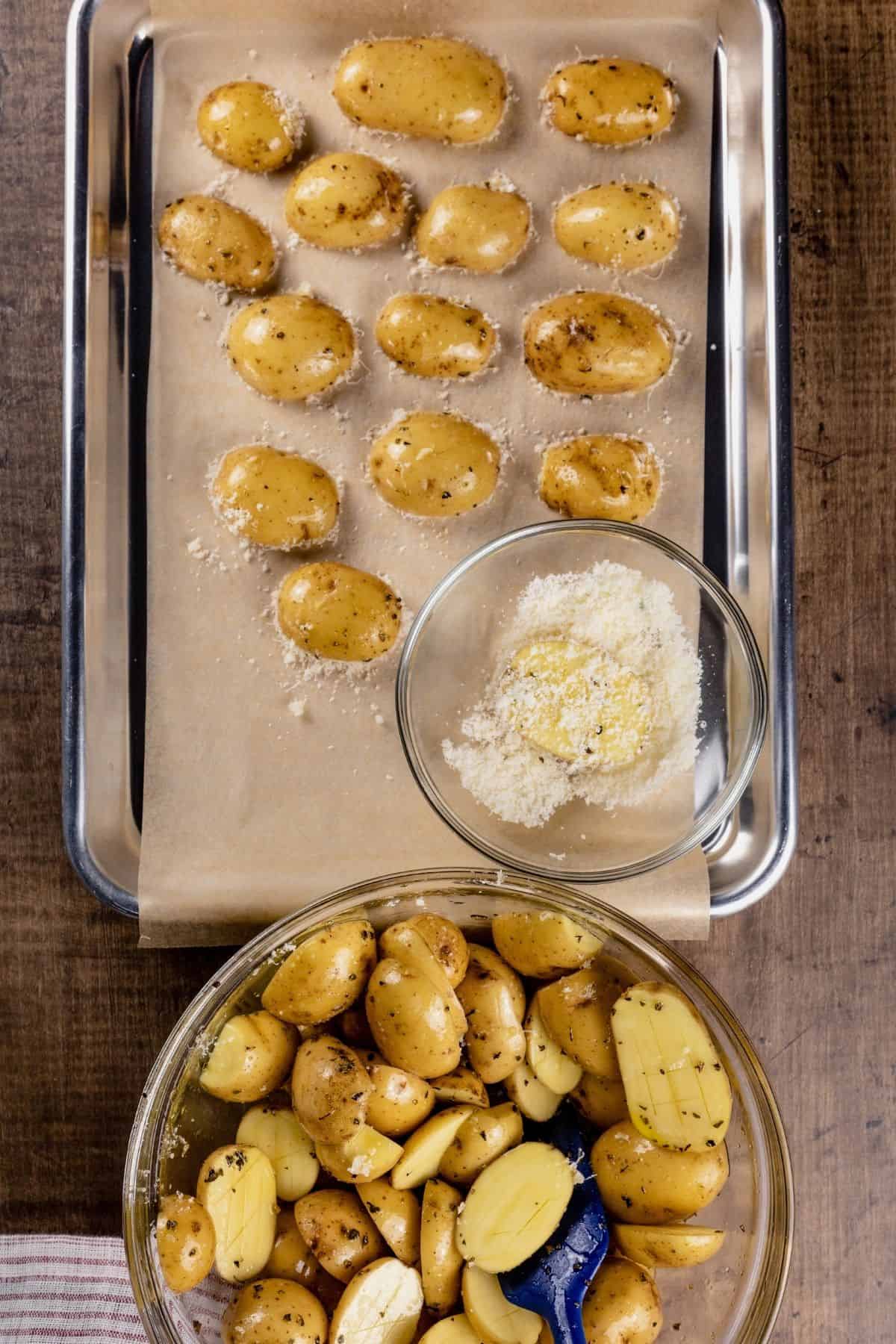 halved potatoes being dipped in parmesan cheese and then placed on a parchment paper lined baking sheet.