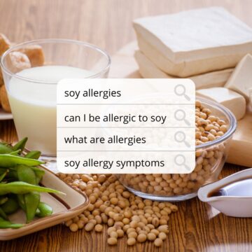 soy based products like edamame, tofu, soy milk, and soy sauce are seen on a wood table top. a text search box asks questions like can I be allergic to soy overlaid on the image.