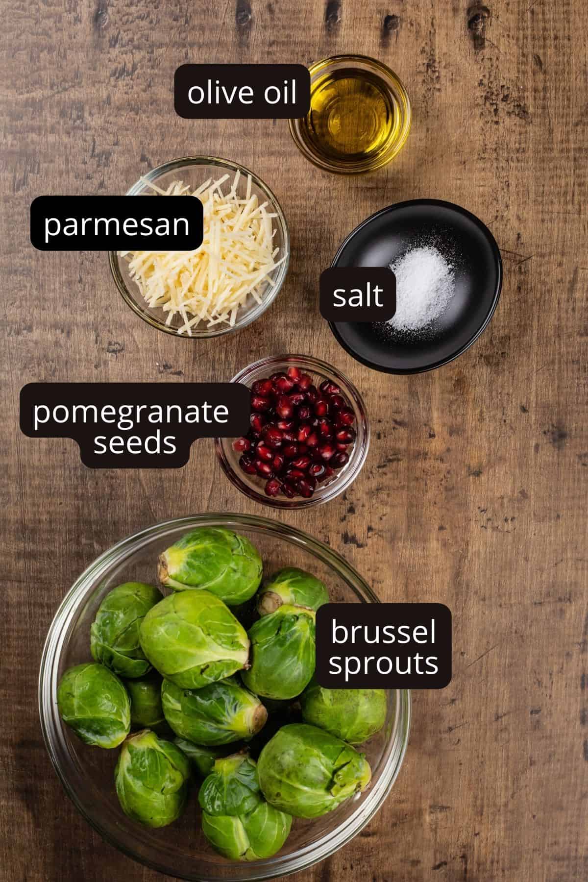 ingredients for roasted sprouts in various glass bowls on a wood table. black and white labels have been added to name the ingredients.