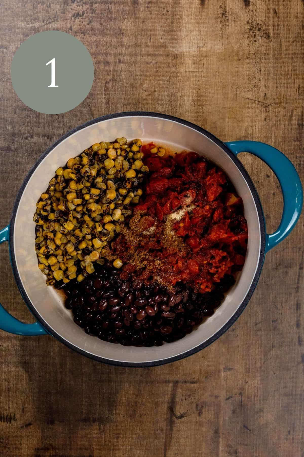 A blue ceramic cooking pot is on a wood table filled with the ingredients to make the bean filling for a burrito bowl. A green circle with the number 1 is in the top left corner.
