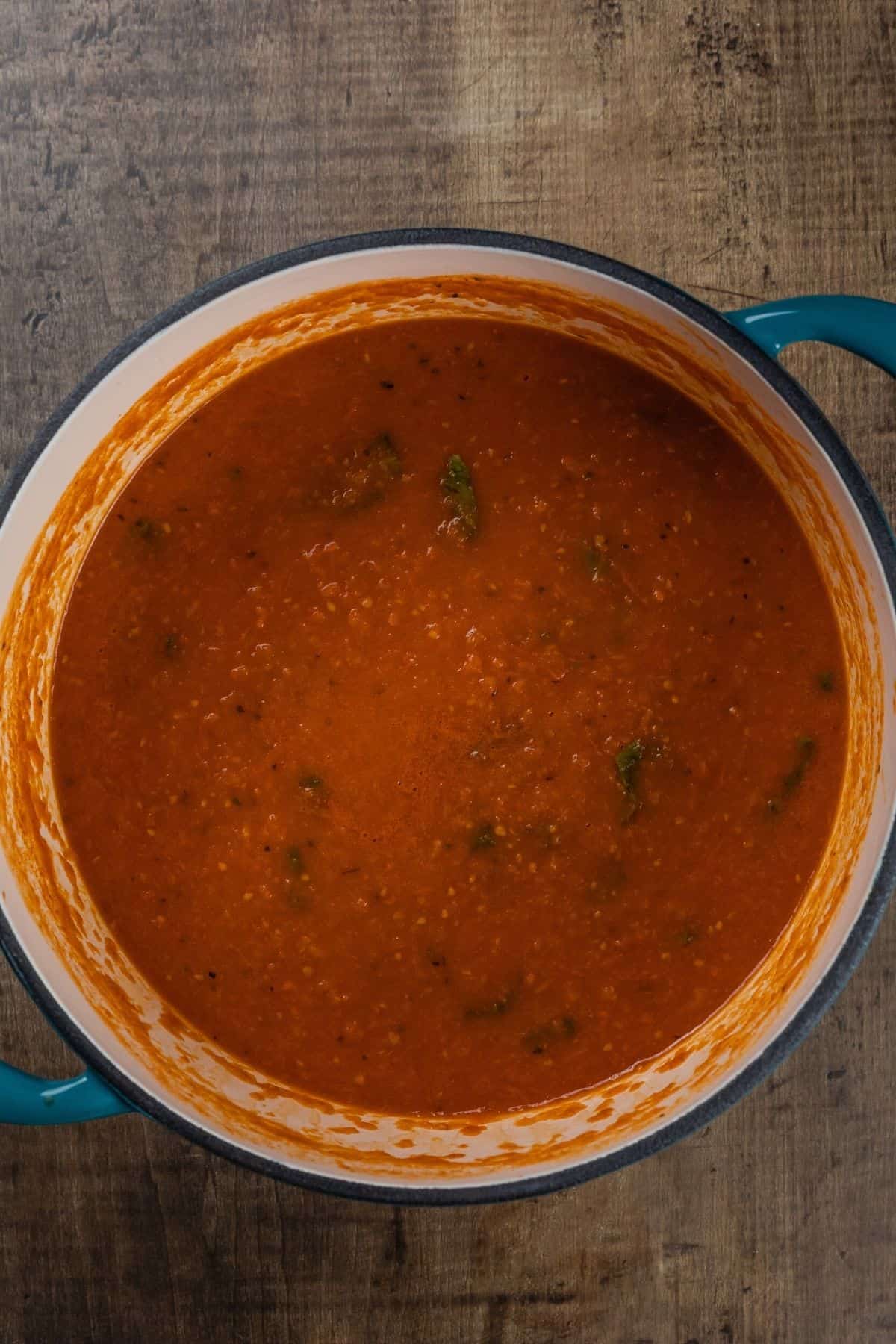 The finished cooking tomato soup in a large blue ceramic pot.