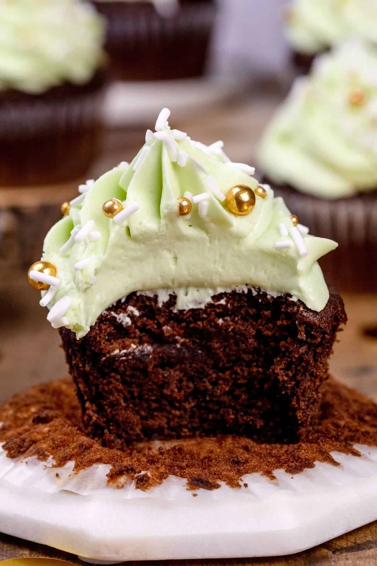 Closeup of a mint chocolate cupcake with a bite taken out of it. You can see the soft and fluffy inside of the cupcake.