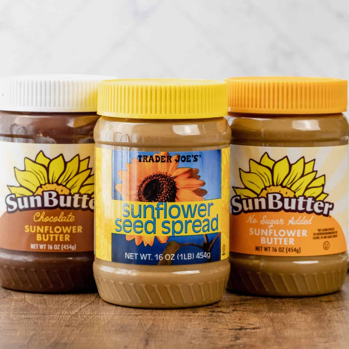 3 types of sunflower seed butter on a wood table in the kitchen. It includes Trader Joe's Sunflower Seed Butter and SunButter.