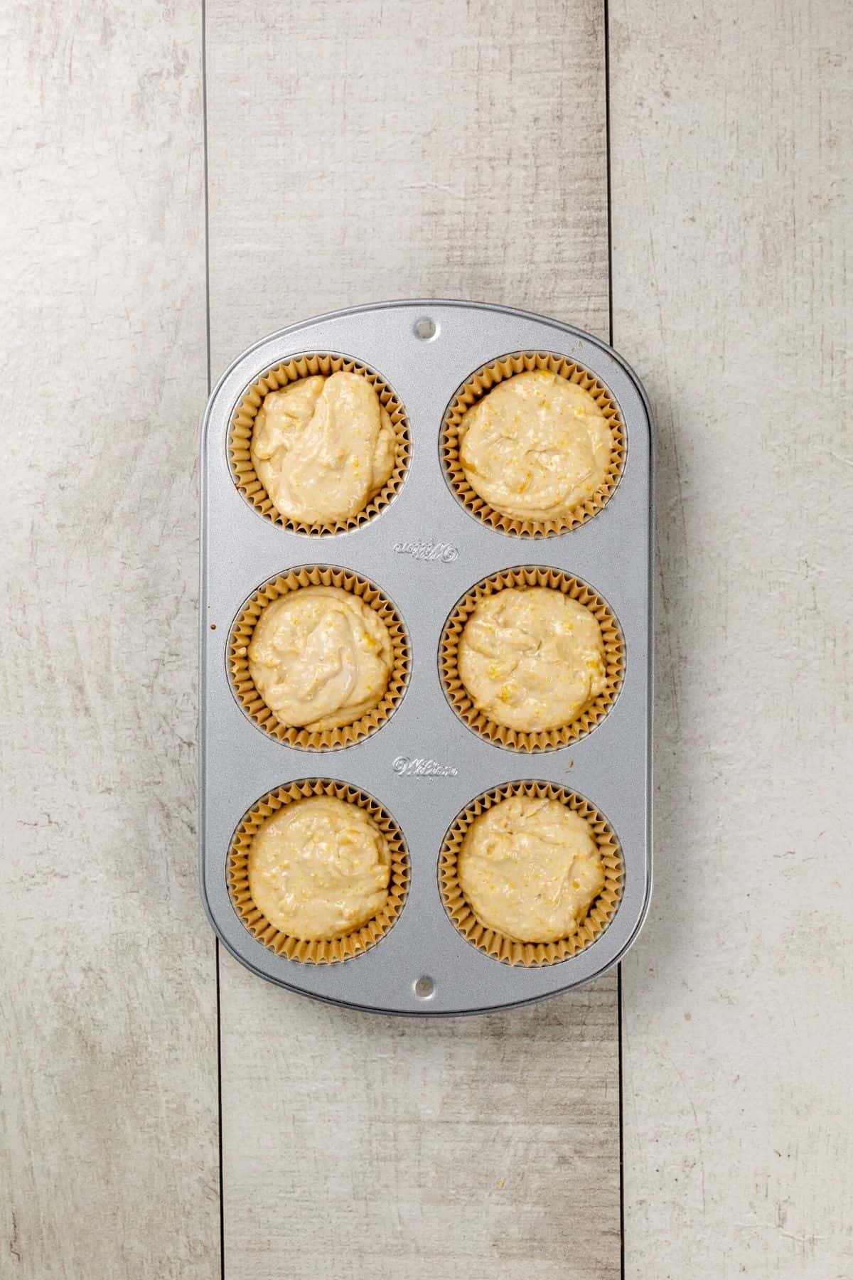 6 unbaked cornbread muffins in a muffin tray.