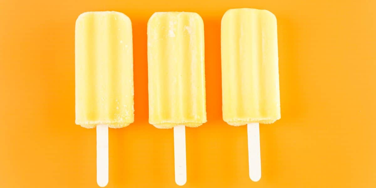 3 yellow popsicles on a bright orange background.