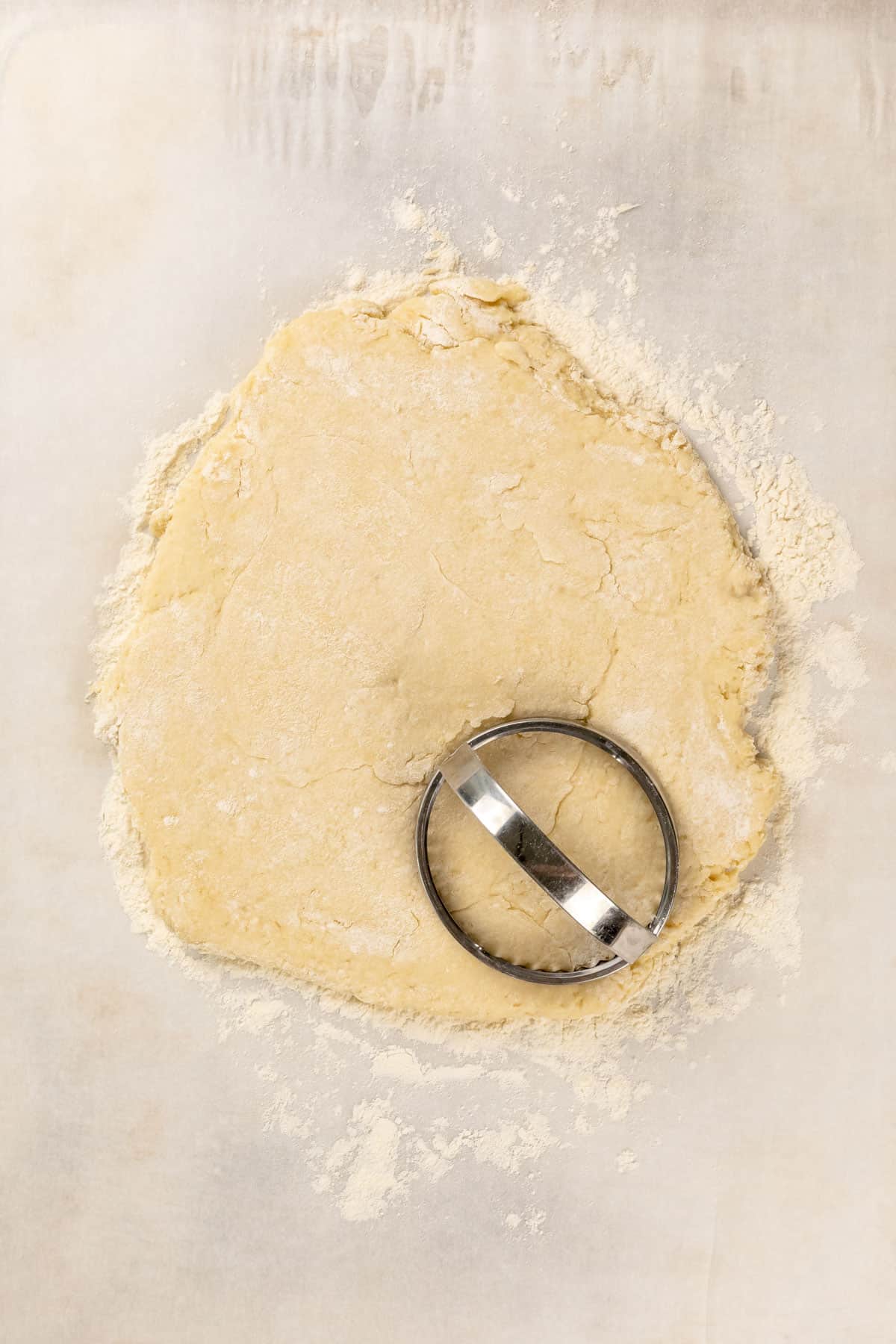 The rolled dough dough for vegan shortcakes with a round biscuit cutter in the bottom right.