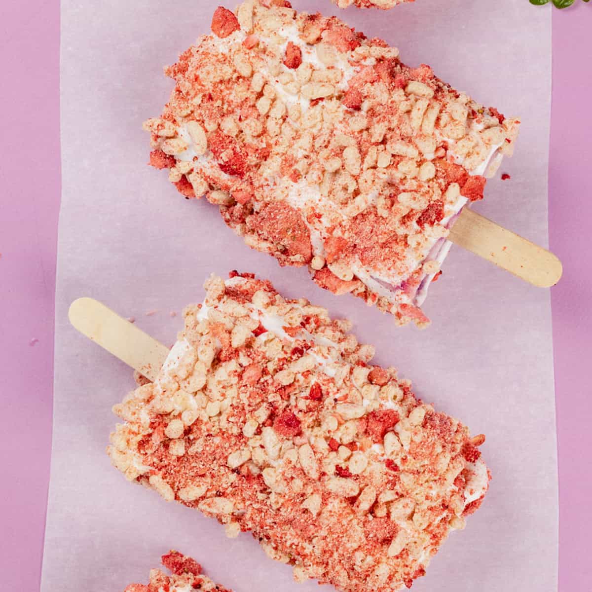Many dairy free strawberry shortcake ice cream bars on a bright pink background.