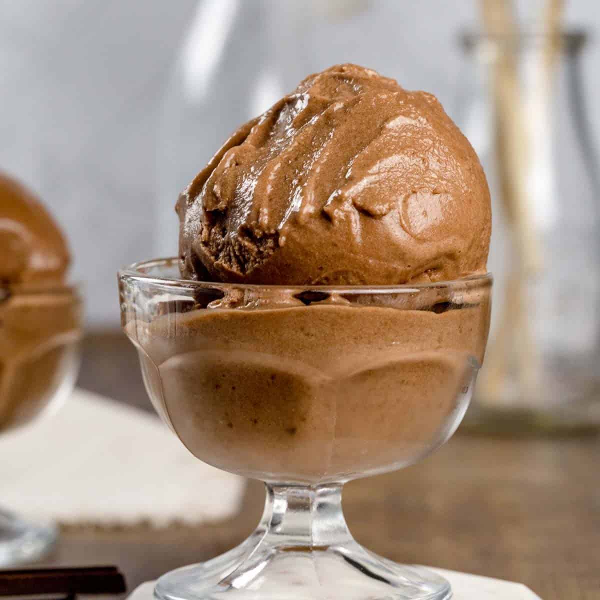 A close up of a glass bowl filled with scoops of chocolate nice cream.