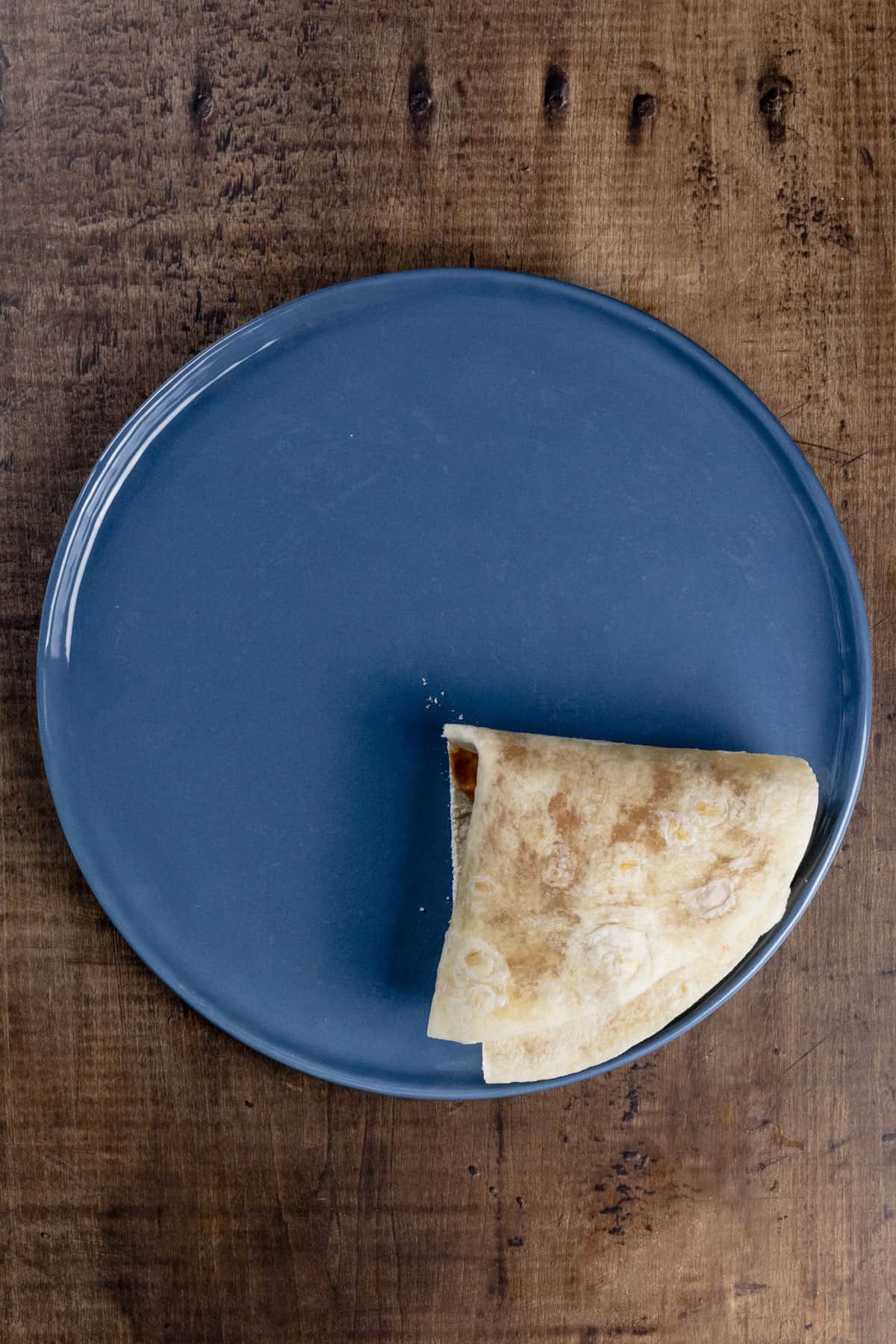 Showing the final step of folding it into a triangle on a blue plate.