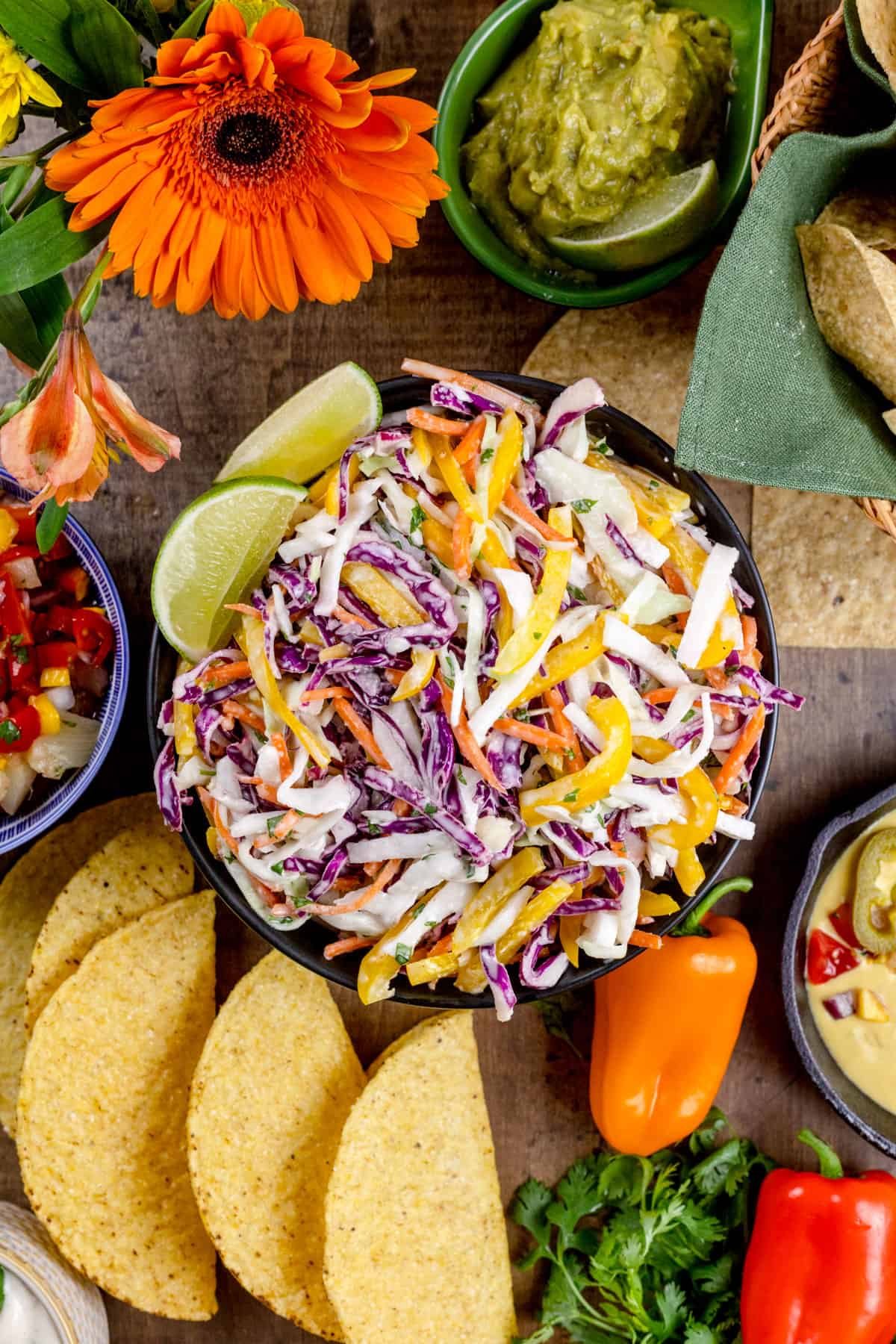 Looking down at a big bowl filled with jicama cabbage coleslaw that is surrounded by ingredients for taco night.