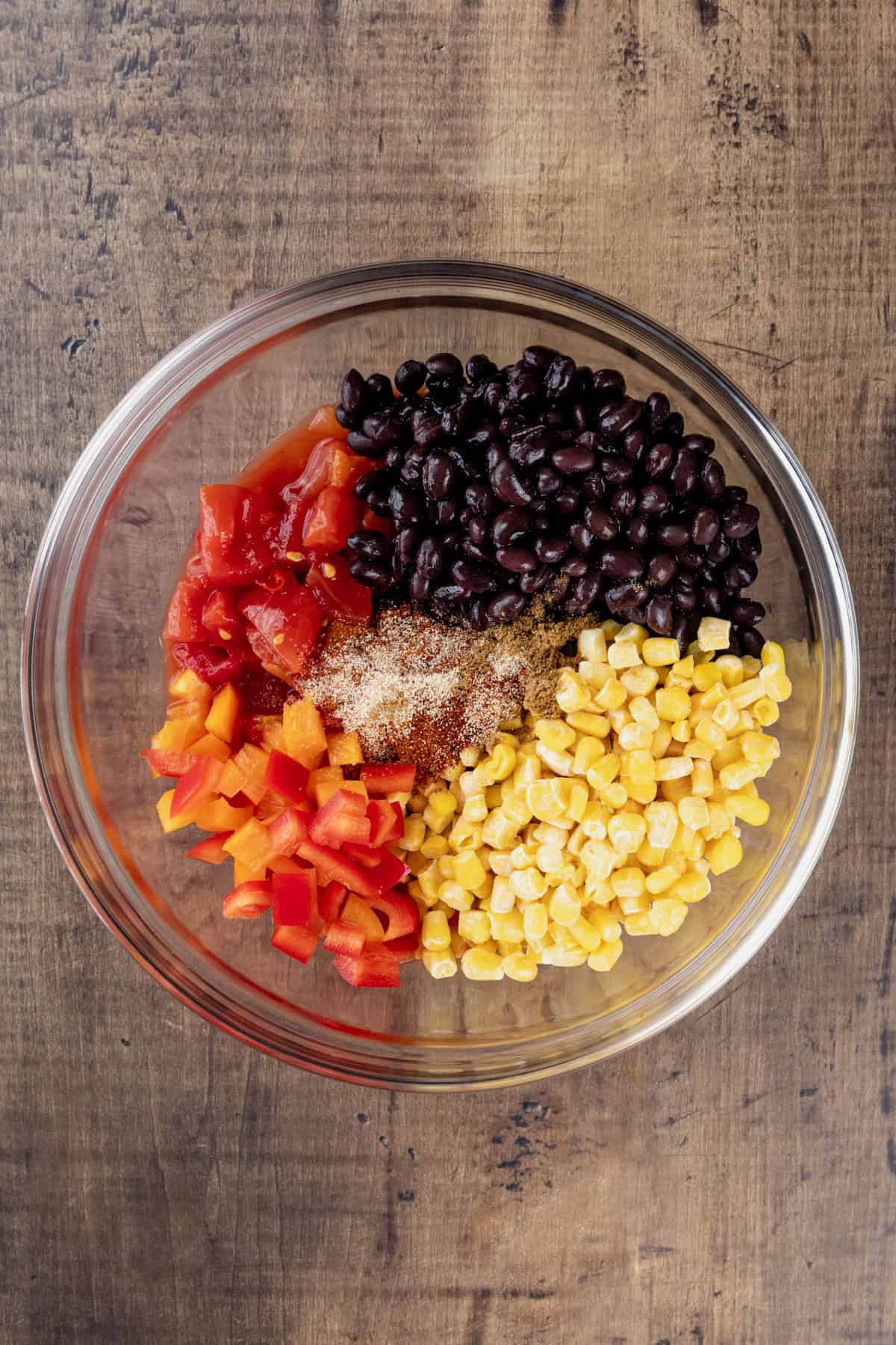 A glass bowl filled with the bean and veggie layer of the taco casserole.